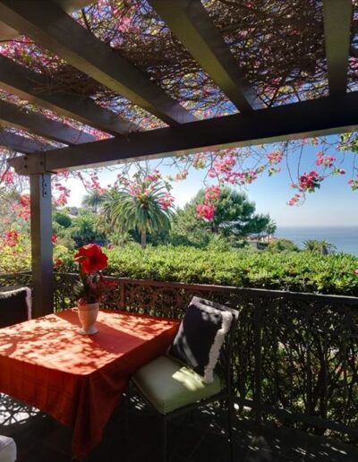 A balcony with a table and chairs overlooking the ocean.