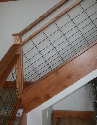 A wooden stair railing with a black railing.